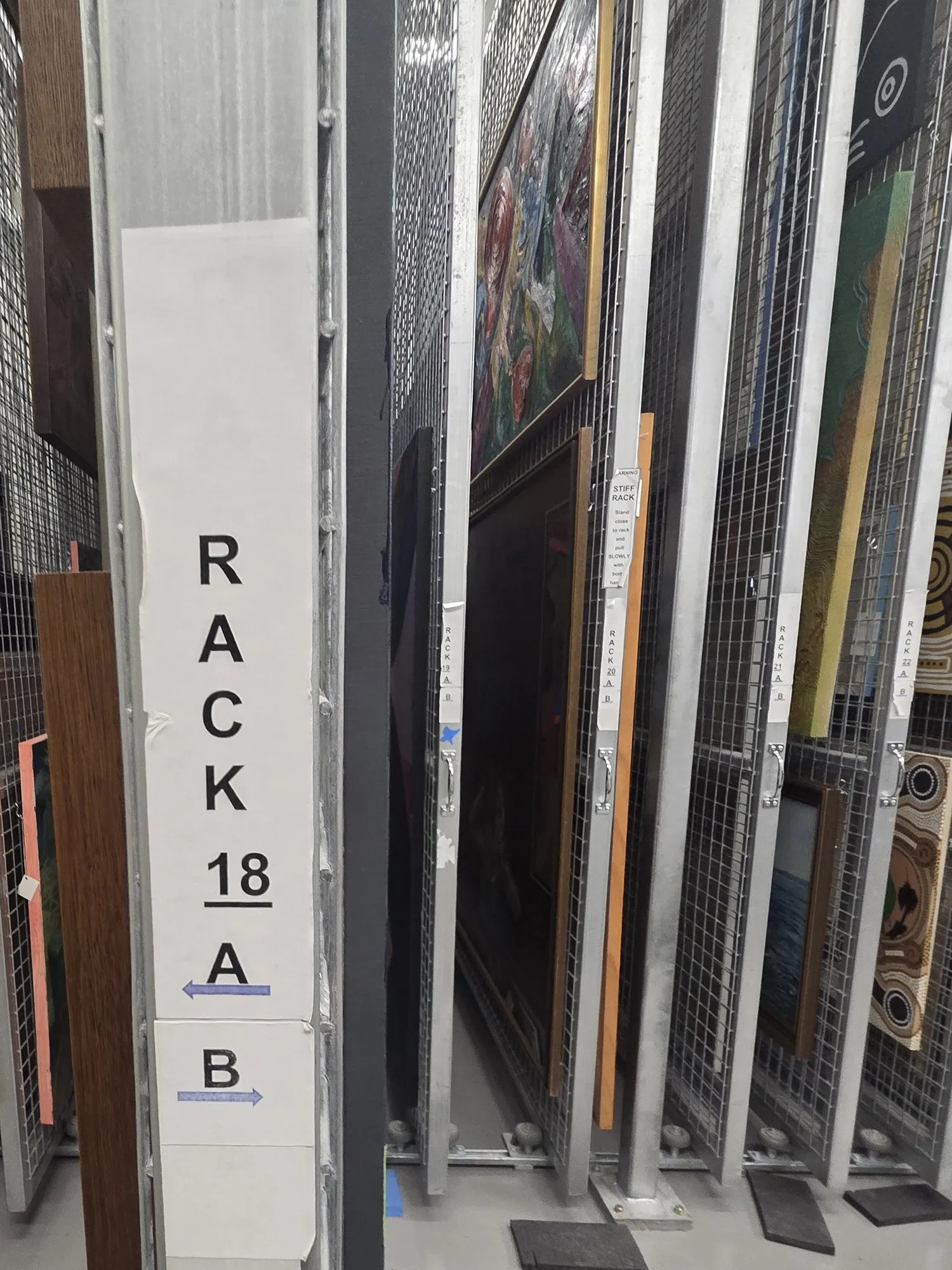 Labelled mobile storage racks holding framed artworks in a collection store